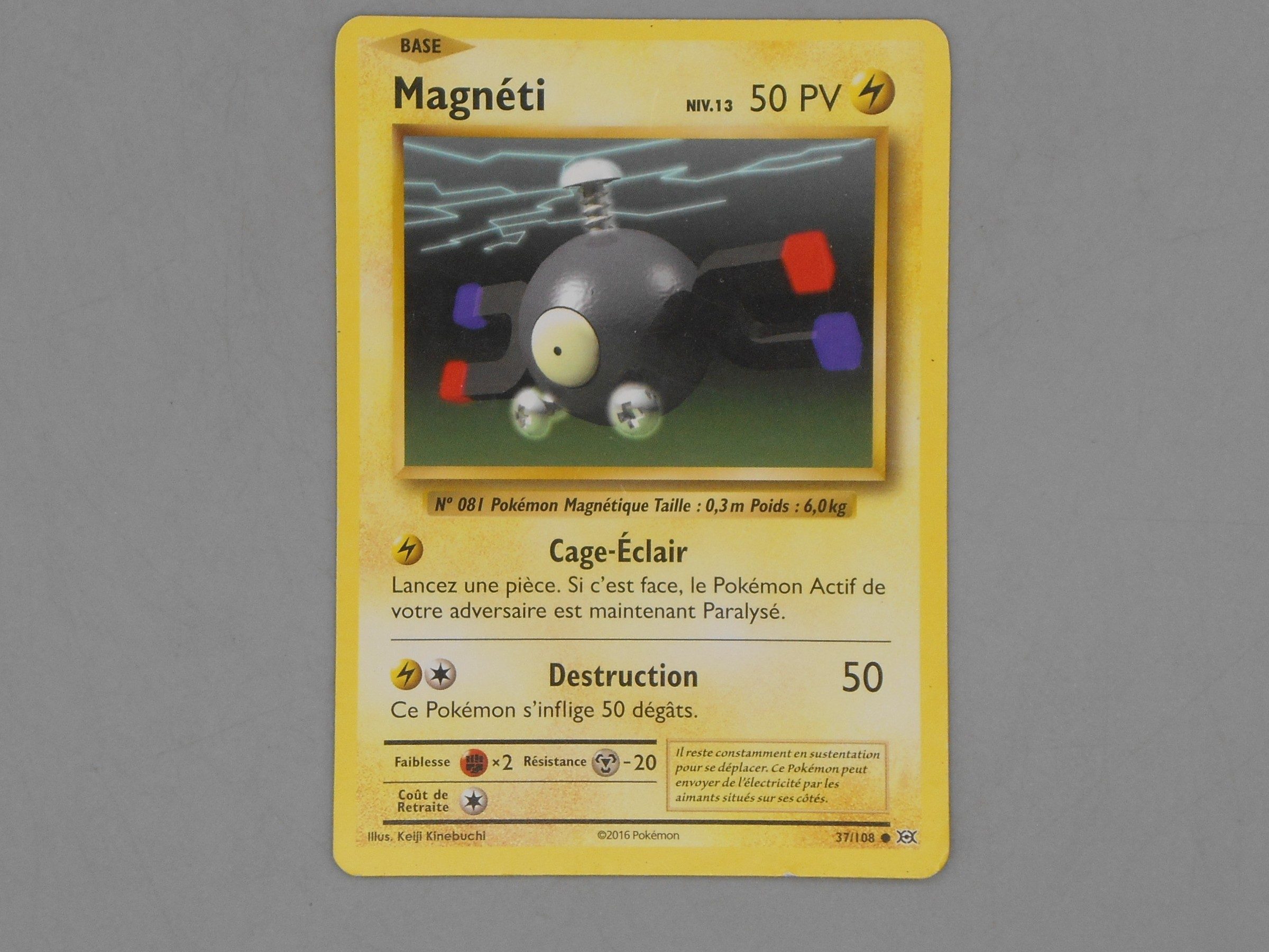 Carte Pokémon Magnéti posée sur une table, avec le numéro et le symbole d'extension visibles
